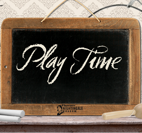 A wooden writing slate with the words 'Play Time' written in chalk in cursive handwriting, a ball and cup toy is at the side